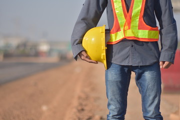 Close up Engineering holding Yellow helmet hard hat safety and Road construction background