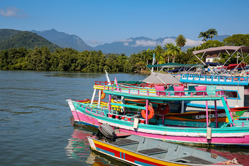 View to colorful tour boats in the water waiting for tourists at a pier, with green mountains in the background, Paraty, Brazil, Unesco World Heritage