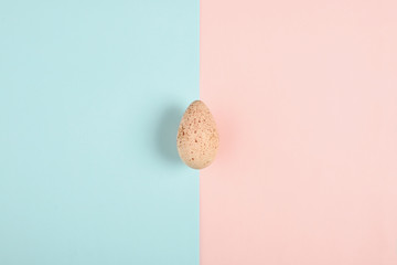 One turkey egg on colored paper background. Food concept in minimal style. Top view. Alternative decoration.