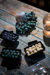 Bougies de plusieurs couleurs dans des boites noirs sur une table en chêne massif 