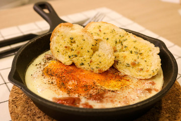 Fried egg on pan with garlic bread
