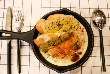 Fried egg on pan with garlic bread
