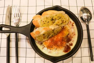 Fried egg on pan with garlic bread