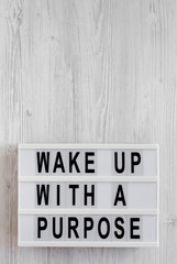 'Wake up with a purpose' words on a modern board on a white wooden surface, top view. Overhead, from above, flat lay. Copy space.