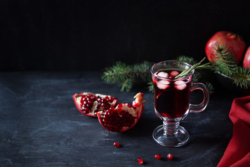 Pomegranate Christmas cocktail with rosemary, champagne, club soda on black table. Xmas drink.