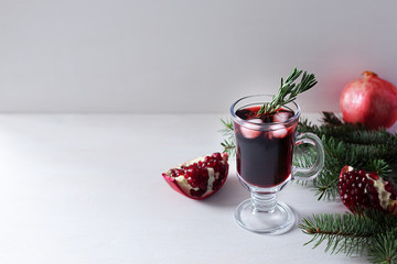 Pomegranate Christmas cocktail with champagne, soda and rosemary on a white table. Xmas drink.
