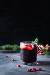 Pomegranate Christmas cocktail with champagne, club soda and rosemary on black table. Xmas drink.