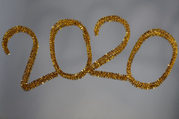 New year 2020 inscription made of glittering tinsel with a silver background.