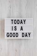 'Today is a good day' words on a lightbox on a white wooden background, top view. Overhead, from above, flat lay.