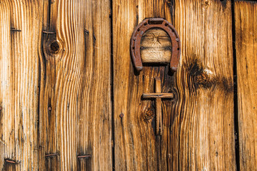 Verwitterte Holztür mit Kreuz und Hufeisen quer