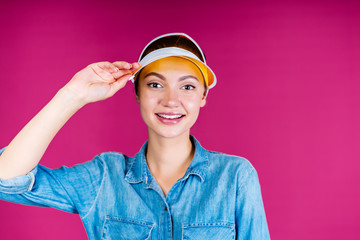 a girl with a healthy blush on her face, in the visor holds her hand and smiles sweetly. background pink