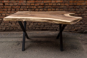 Wooden stylish table made of solid walnut with epoxy resin on the background of a brick wall