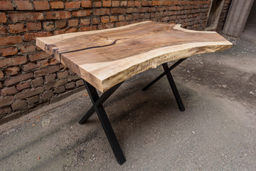 Fototapeta na wymiar Wooden stylish table made of solid walnut with epoxy resin on the background of a brick wall