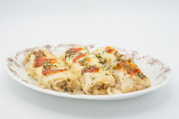 Canelones (cannelloni) with meat filled pasta and cheese and tomato on a plate