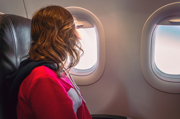 Young woman sitting in airplane seats looking out the window