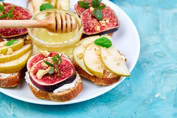 Antipasto. Italian food.  Bruschetta and Crostini with pear, ricotta cheese, honey, figs, nuts and herbs. Breakfast toasts or snack sandwiches. Top view. Copy space.