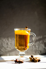 Hot winter drink with cinnamon and lemon on bright sunny day