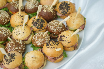 Mini burgers with meat and fish on the table prepared for the guests of the event.