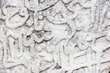 fragment of a gray stone wall depicting oriental patterns hieroglyphs