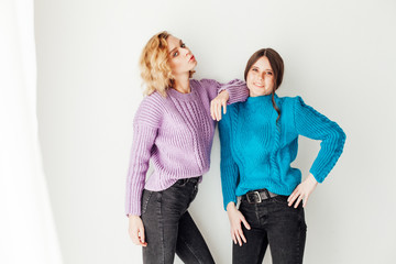 Two beautiful fashionable female girlfriends in sweaters in the room