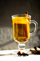 Hot winter drink with cinnamon and lemon on bright sunny day
