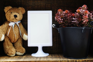 Blank Display frame stand with teddy bear on wooden background