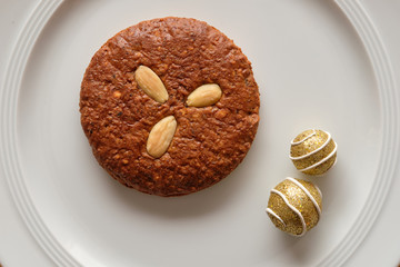 Still life with one delicious brown Elisengingerbreads with almonds and christmas decoration  lying on a pure white porcelain plate