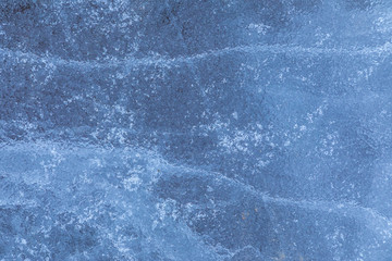 The macro or closeup shot of ice texture or background on the puddle or pool in the frost winter weather