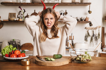 Image of angry cute woman making horns with bell peppers