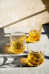 Whiskey in glasses on table in bright sunlight, yellow drink