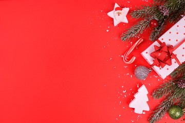 Christmas composition on a red background.  Flat lounger, top view, copy space for your text. Christmas decorations gifts, spruce, toys, candies, star, on a snowy red background.