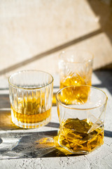 Whiskey in glasses on table in bright sunlight, yellow drink