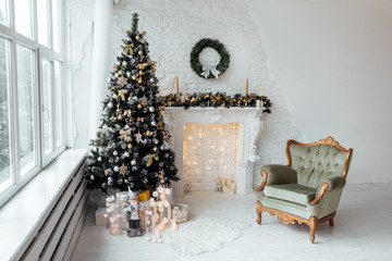 Beautiful holiday decorated room with Christmas tree with present boxes under it in white and blue. Large panoramic window, fireplace and armchair in classic style