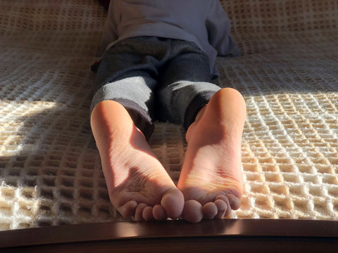 Boy's feet on bed close-up. Boy lying on bed and reading a book