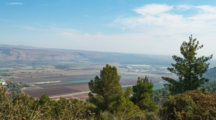 Hula Lake Park on the left and the hula nature reserve on the right from near the reut museum with trees in the foreground and the golan heights in the background