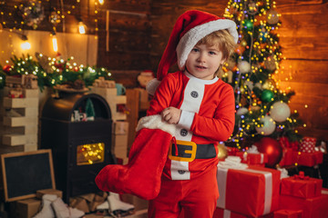 Obraz na płótnie Canvas Christmas kid. Happy little smiling boy with Christmas gift socks. Happy kid having fun with gift. Happy Kid is waiting for the New Year.