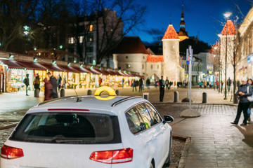 Tallinn, Estonia. Taxi Car Parking Near Viru Gates Entrance To Old Part Town Estonian Capital. Famous Landmark Viru Gate In Street Lighting At Evening Night Illumination. Christmas, Xmas, New Year