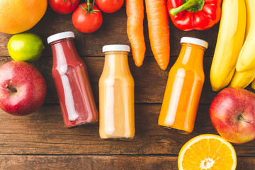 Overhead shot of colourful juices in bottles on old wooden table with ingredients