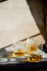 Whiskey in glasses on table in bright sunlight, yellow drink