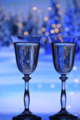Two glasses with champagne sparkling wine on a festive blue background with lights and bokeh and a toy rat. The atmosphere of celebration and happiness.