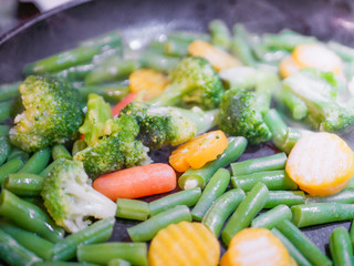 Vegetables fried in a pan close-up. Steam is coming. Defocus. vegetarian barely. Eco food.