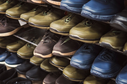 Close Up Of Shopping Stand With Budget-freindly Unisex Shoes For Autumn And Spring. Shelves With Men's Sport Shoes In Shoe Market. Junior Footwear Fashion. Buying Cheap Male Boots. Pairs Of Footgear.