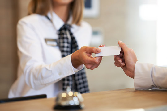 Receptionist giving key card to businesswoman at hotel front desk
