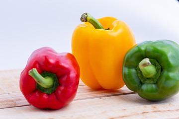 Colorful peppers placed on a wooden table.