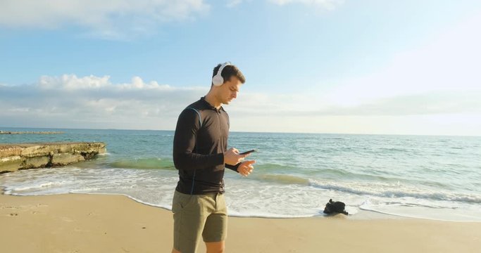 Fit male runner training on the summer beach and listen to music against beautidul sky and sea , UHD 4K