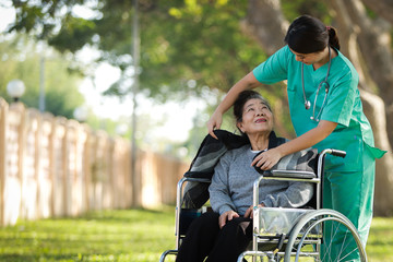 Asian senior woman sitting on the wheelchair  with woman in doctor uniform in the park hospital