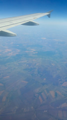 Fototapeta premium Wing of an airplane flying above the fields