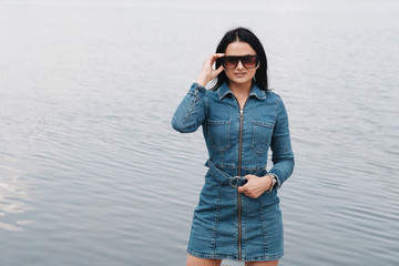 Portrait of One Beautiful Brunette Girl Dressed in Jeans Denim Overalls Spends Leisure Time