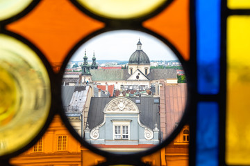 The roofs of Krakow's Old Town through the colored stained glass from the Town Hall Tower on a summer day.  In transparent Circle - St. Anne's Church and tenement house "Kamienica Pod Jagniemi". © edita