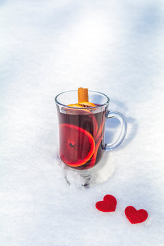 Cup with delicious mulled wine and spices on a snow covered, Valentines Day greeting card